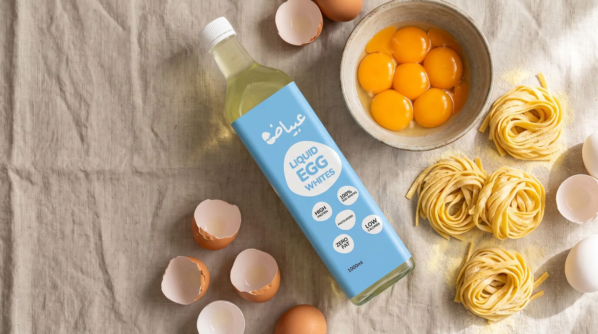 A 3abayad bottle beside a bowl of egg yolks and nests of fresh Jood egg pasta