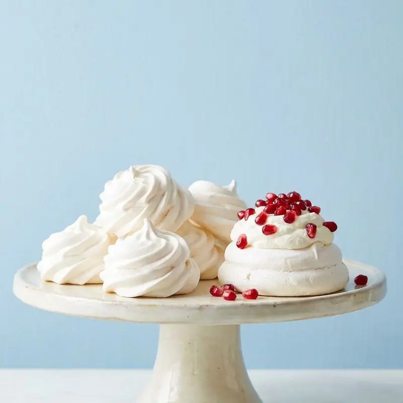 Meringue kisses and a small pavlova with cream and pomegranate seeds